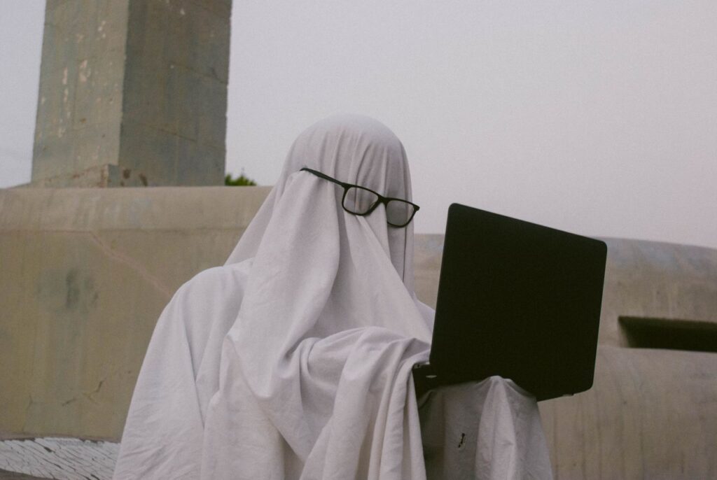 Crafting Captivating Headlines: Your awesome post title goes here A humorous depiction of a person in a ghost costume using a laptop outdoors.